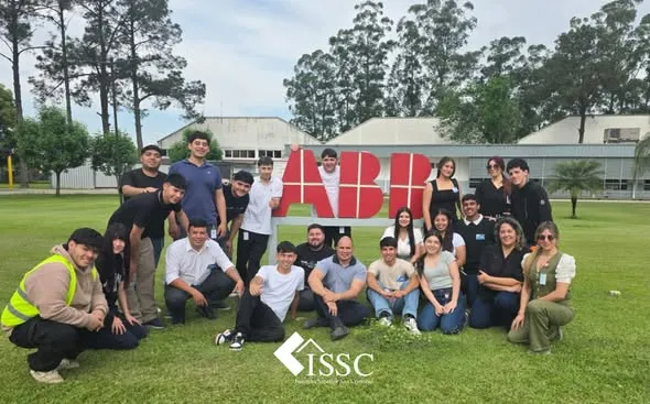 Estudiantes y docentes del ISSC reunidos frente al cartel de ABB durante la visita educativa